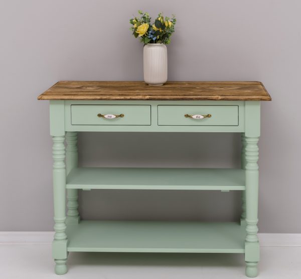 Landelijke smalle sidetable met 2 kleine lades en 2 planken voor opbergruimte. De sidetable heeft mooie lange klassieke poten en de lades gaan open door middel van een handgreep met bloemen erop. De onderkant van de kast heeft de kleur mint en het boven blad heeft de kleur eiken bruin. De kast is gemaakt van massief eiken hout. De kast kan op verschillende manieren geverfd worden in verschillende kleuren en kan op maat gemaakt worden. Villa Laura