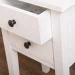 Landelijk nachtkastje met twee kleine lades en hoge pootjes. Gemaakt van massief eiken hout in de kleur wit. Het meubel kan op verschillende manieren geverfd worden in verschillende kleuren en kan op maat gemaakt worden. Villa Laura